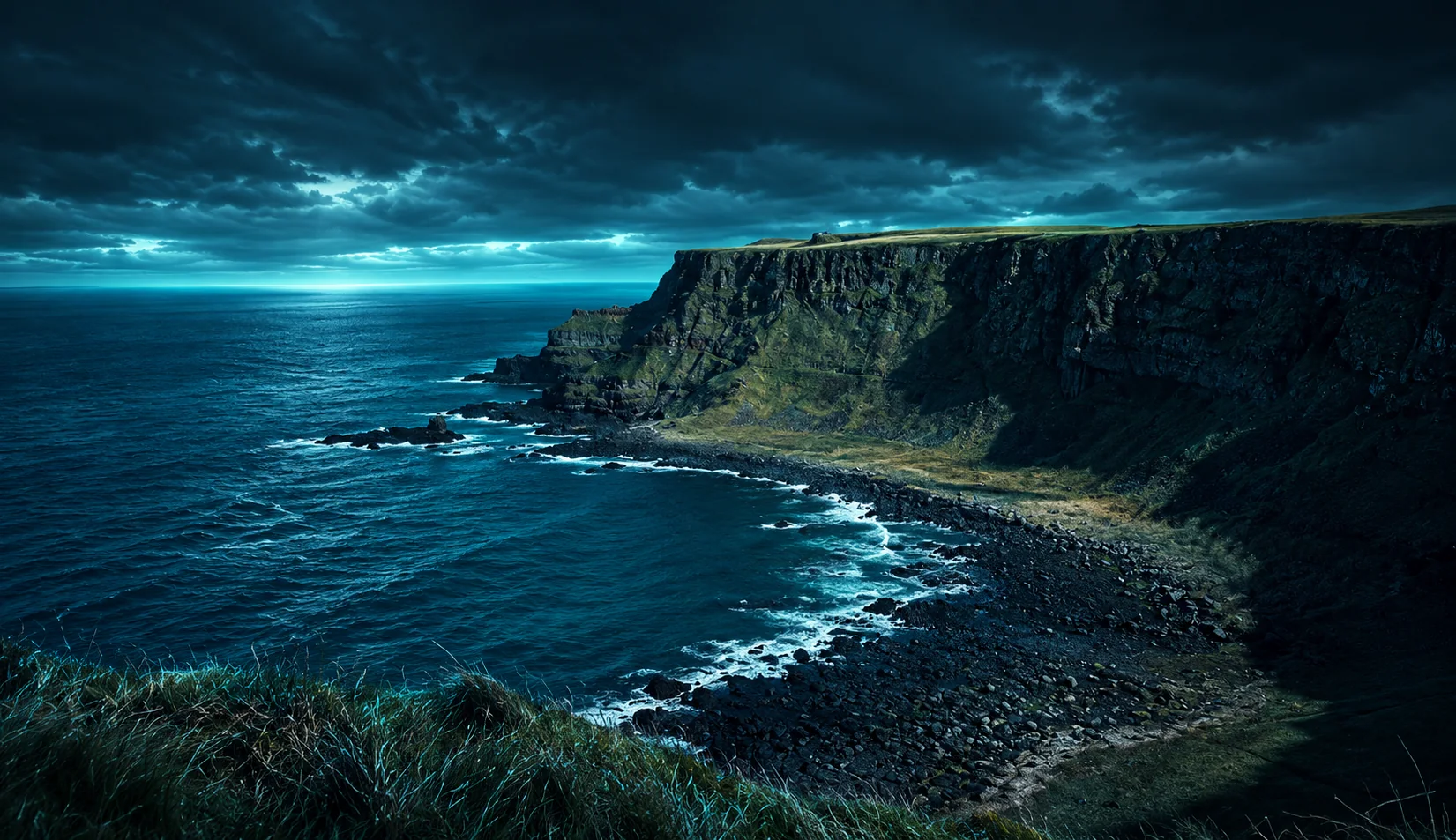 Sea cliffs and a rocky bay on the north coast of Northern Ireland under a stormy sky